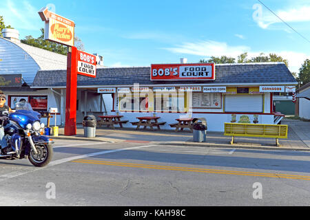 Wie viele saisonale Unternehmen in Geneva-on-the-Lake, Ohio, ist auch Bob's Food Court für die Saison geschlossen, in der ein Motorradfahrer den leeren Streifen bereist. Stockfoto