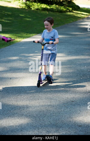 Junge litte Boy außerhalb Reiten sein Roller in der Einfahrt Stockfoto