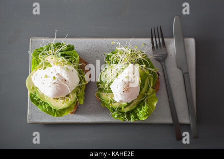 Frühstück Toast mit Avocado, pochierte Eier und Alfalfa Sprossen Stockfoto