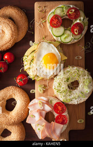 Auswahl an Sandwiches auf Bagels: Ei, Avocado, Schinken, Tomate, Weichkäse, Alfalfa Sprossen Stockfoto