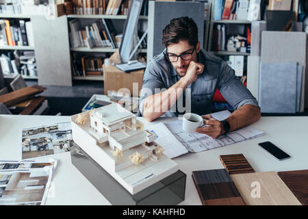 Junge männliche Architekt die Pause von der Arbeit. Kreative Designer im Büro auf der Suche nach Modell mit Tasse Kaffee. Stockfoto