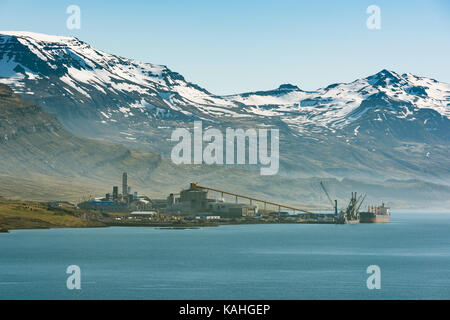 Aluminiumhütte vor schneebedeckten Bergen, Reyðarfjörður, Ostfjorde, Insel Stockfoto