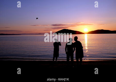 Skiathos, Griechenland. September 13, 2017. Ein Vogel und Urlauber bieten eine Silhouette gegen einen schönen Sonnenuntergang am Strand auf der Insel Tsougrias. Stockfoto