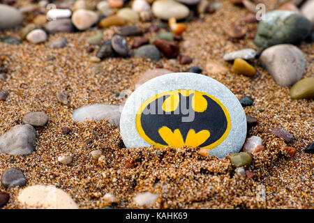 Paphos, Zypern - 22. November 2016 Kiesel mit gemalten Zeichen Batman am Strand mit Sand und Kieselsteinen. Stockfoto