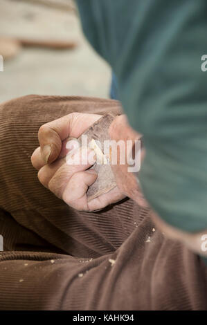 Feuerstein-Knapping-Demonstration, indem man lernt, mit Knochenwerkzeugen von Hand eine Pfeilspitze aus Feuerstein zu machen Stockfoto