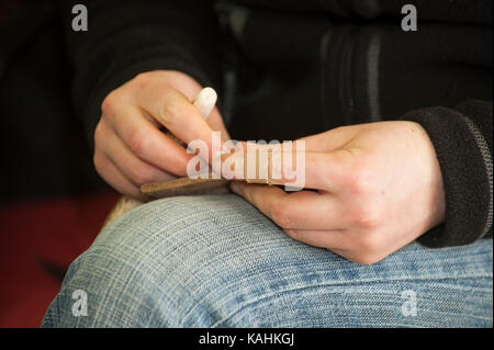 Feuerstein-Knapping-Demonstration, indem man lernt, mit Knochenwerkzeugen von Hand eine Pfeilspitze aus Feuerstein zu machen Stockfoto