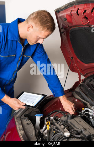 Nahaufnahme der Mechaniker mit digitalen Tablet während der Prüfung den Motor in einer Garage. Stockfoto