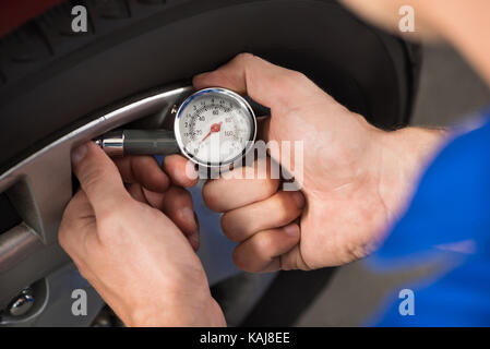 Nahaufnahme der Mechaniker prüfen Luftdruck im Reifen Stockfoto