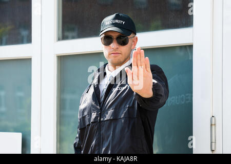 Nahaufnahme eines männlichen Security Guard, Stop-Schild mit Sonnenbrille tragen Stockfoto