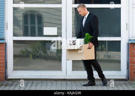 Unglückliche junge Unternehmer seine Habseligkeiten tragen in Feld, nachdem er gefeuert Stockfoto