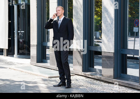 Junge Unternehmer sprechen gerne draußen auf Telefon Stockfoto