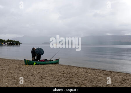 Fischer, die darauf warten, den Regen zu stoppen, um in Loch Lomond Luss, am Westufer von Loch Lomond, Argyll & Bute, Schottland, Großbritannien, zu fischen Stockfoto