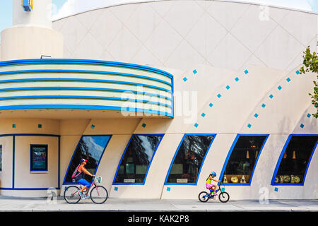 Mutter und Tochter Radfahren Vergangenheit der Art-déco-Stil Kino in der Feier, Orlando, Florida, USA Stockfoto