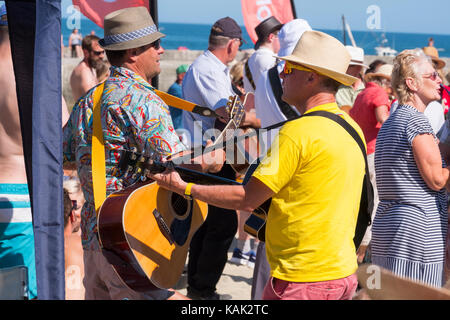 Die Gitarristen spielen an der Gitarre am Strand Veranstaltung in Lyme Regis, Dorset, Großbritannien. Stockfoto