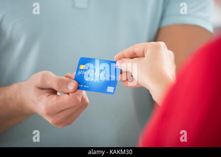 Zugeschnittenes Bild der Verkäufer die Kreditkarte von weiblichen Kunden in Clothing Store Stockfoto