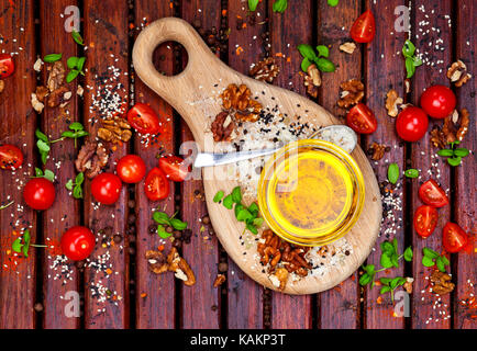 Gewürze, Tomaten, Basilikum und Pflanzenöl auf dunklen Holztisch, Ansicht von oben Stockfoto