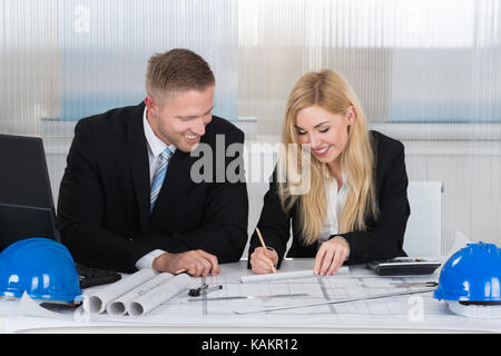 Selbstbewussten jungen Architekten diskutieren über Blueprint am Schreibtisch im Büro Stockfoto