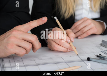Zugeschnittenes Bild von jungen Ingenieuren diskutieren über Blueprint am Schreibtisch im Büro Stockfoto