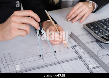Zugeschnittenes Bild junger Architekten arbeiten an Blueprint am Schreibtisch im Büro Stockfoto