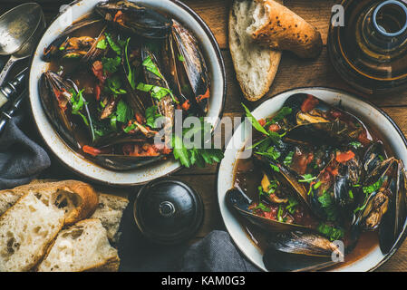 Gekochte Miesmuscheln in Tomatensauce und Bier über Holz- Hintergrund Stockfoto