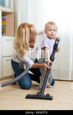 Reinigung der Zimmer zusammen - die Mutter und ihr Kind Sohn mit Staubsauger absaugen Stockfoto