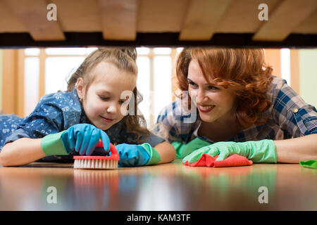 Mutter und Tochter sie die Reinigung im Haus. Glückliche Frau und Kind Mädchen wischte den Boden. Stockfoto