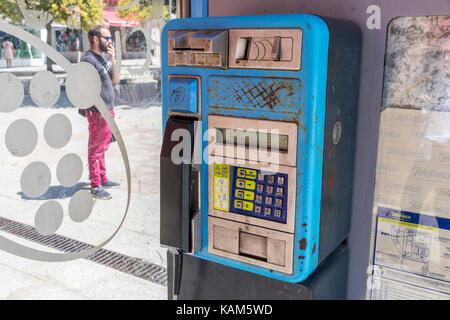 Eine der alten Telefonica Telefonzellen in Bueu, Galicien, Spanien, mit einem Mann rauchen im Hintergrund Stockfoto