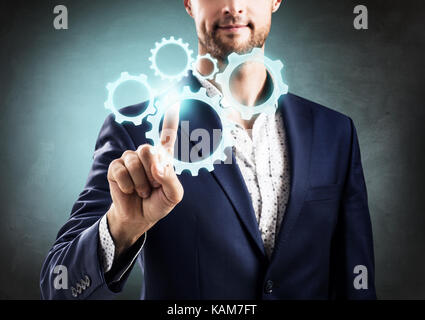 Geschäftsmann Druck auf die Gruppe der Zahnräder. Stockfoto