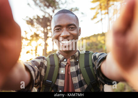 Lächelnden jungen afrikanischen Mann unter selfies während allein wandern im Freien Stockfoto