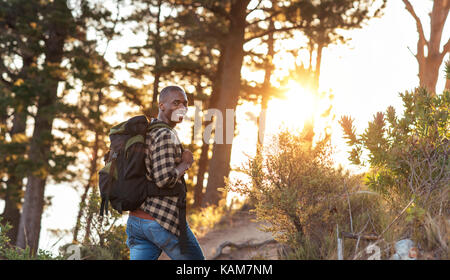 Lächelnd afrikanischer Mann Wandern in einem Wald am Nachmittag Stockfoto