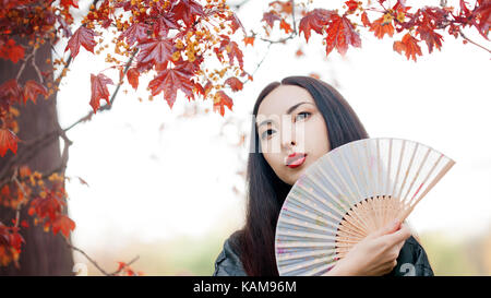 Asiatische Mädchen im Kimono auf dem Hintergrund der Rote Ahorn Stockfoto