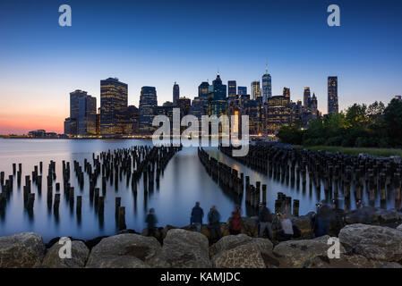 Wolkenkratzer von Manhattan bei Sonnenuntergang und Holz-pilings aus Brooklyn Bridge Park. Manhattan, New York City Stockfoto