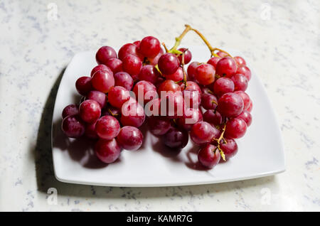 Ein studio Foto aus einem Bündel von 'flame' (Vitis vinifera) Trauben auf einen Servierteller Stockfoto