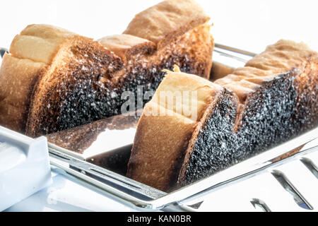 Burnt Toast im Toaster. Gebratene Scheiben Toast im Toaster. Eine Nahaufnahme eines Gebäck in einem schiebeschalter Gerät. Stockfoto