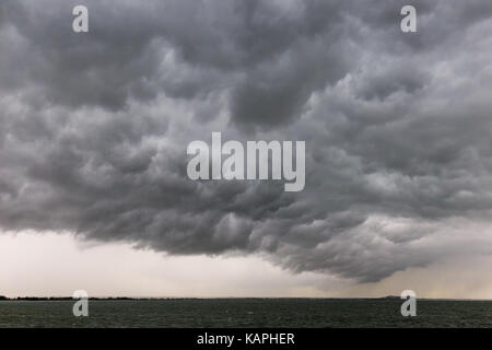Einige spektakuläre und bedrohliche Wolken über einem See, mit einem weit entfernten Insel im Hintergrund Stockfoto