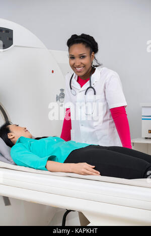 Lächelnd weibliche Radiologen stehen Patienten, die sich einer CT-SCA Stockfoto