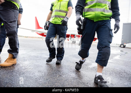 Niedrige Abschnitt der Arbeitnehmer gehen auf nassen Landebahn Stockfoto