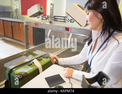 Frau Scannen Tag auf Gepäck am Flughafen Check-in Stockfoto