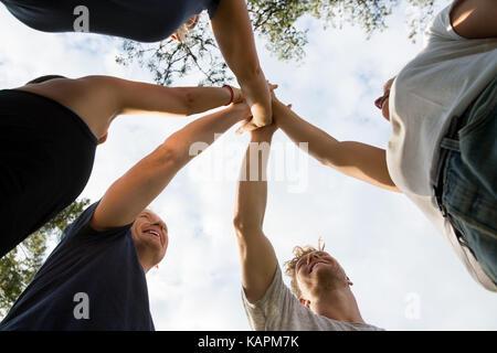 Low Angle View von Freunden Stapeln Hände gegen den Himmel Stockfoto