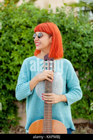 Rothaarige Frau mit einer Gitarre in einem Park mit der Musik genießen. Stockfoto