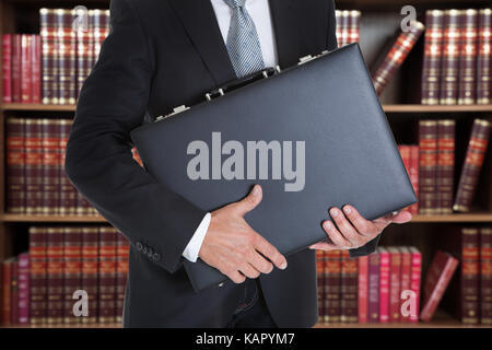 Mittelteil der Geschäftsmann holding Aktenkoffer im Büro Stockfoto