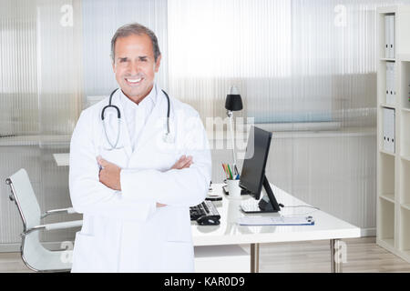 Portrait von zuversichtlich männlicher Arzt in der Klinik stehen Arme gekreuzt Stockfoto