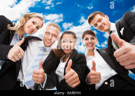 Low Angle Portrait von zuversichtlich Business Team mit Daumen nach oben gegen den Himmel Stockfoto