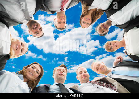 Direkt unter Portrait von vielfältigen Geschäft Leute bilden huddle gegen Sky Stockfoto