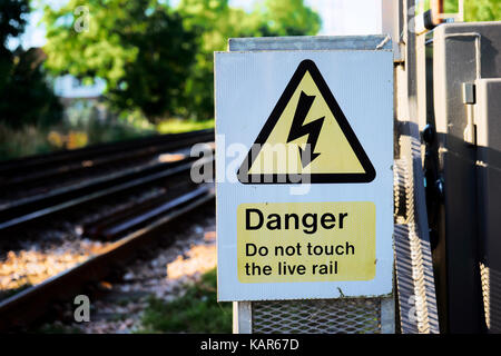 Die dreieckige gelbe Zeichen der Gefahr durch Stromschlag an einem lokalen Bahnhof, Großbritannien Stockfoto