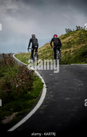 Radfahren Paar klettern Große Dun fiel in den Pennines, Cumbria, Großbritannien Stockfoto