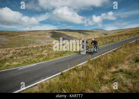 Radfahren Paar klettern Große Dun fiel in den Pennines, Cumbria, Großbritannien Stockfoto