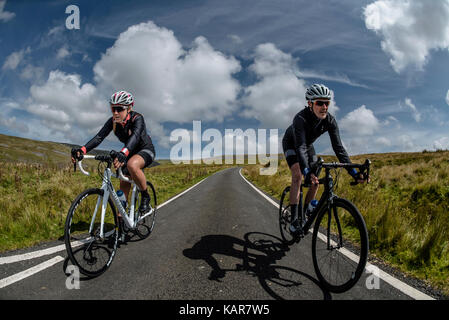 Radfahren Paar klettern Große Dun fiel in den Pennines, Cumbria, Großbritannien Stockfoto