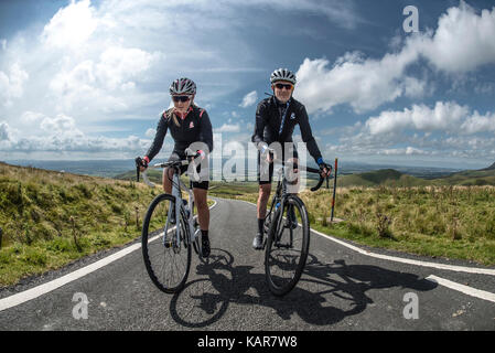 Radfahren Paar klettern Große Dun fiel in den Pennines, Cumbria, Großbritannien Stockfoto