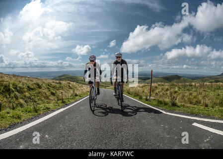 Radfahren Paar klettern Große Dun fiel in den Pennines, Cumbria, Großbritannien Stockfoto